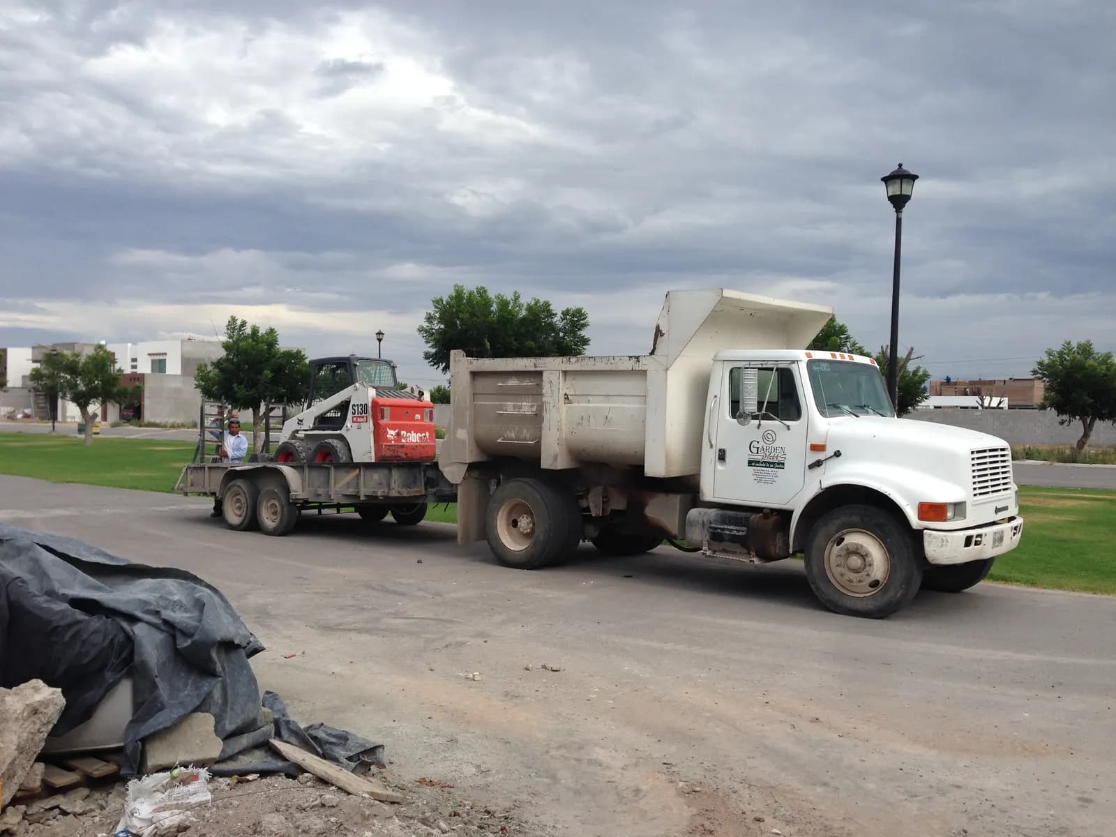 Camión de volteo de Garden Plus remolcando el minicargador Bobcat