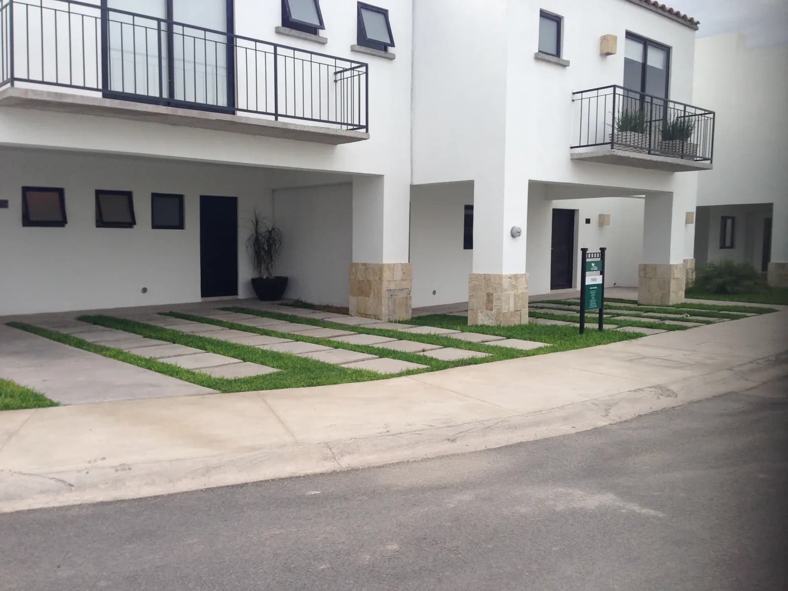 Pasto y huellas de concreto frente a las casas